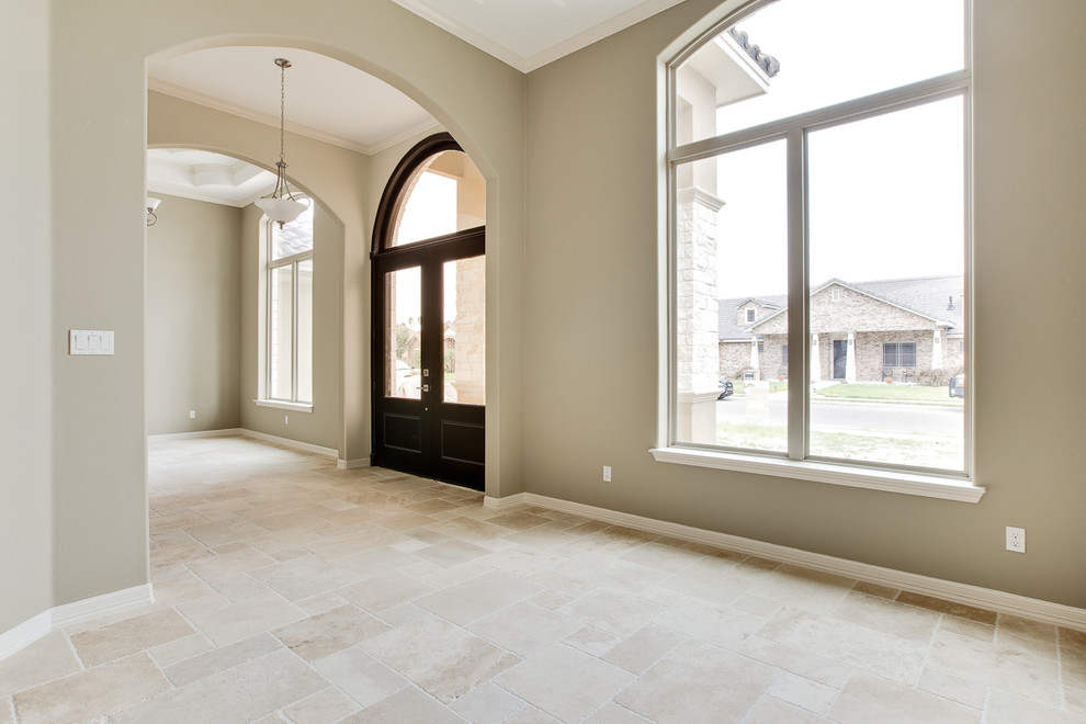 Example of a large travertine floor front door design in Austin with beige walls and a dark wood front door