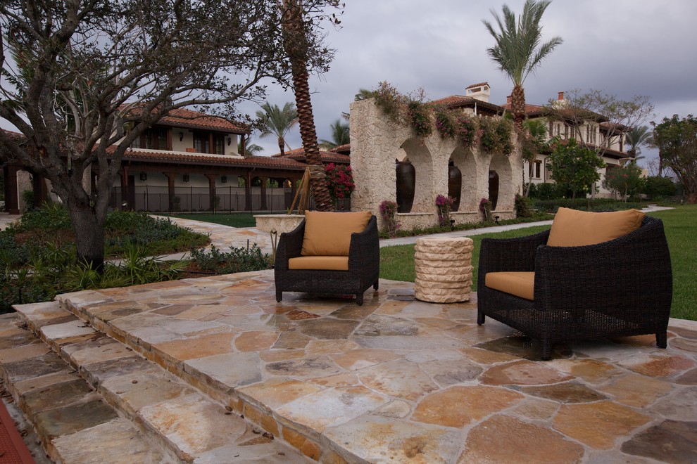 Inspiration for a mid-sized mediterranean backyard patio in Miami with natural stone pavers and no cover.