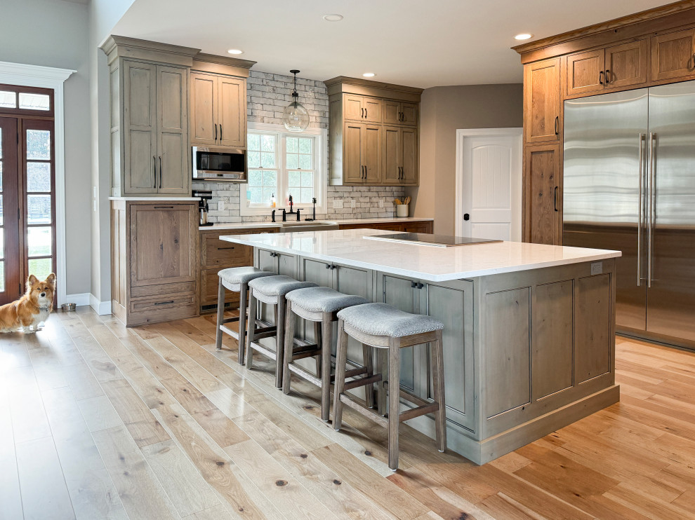 Inspiration for a large transitional l-shaped light wood floor eat-in kitchen remodel with a farmhouse sink, beaded inset cabinets, quartz countertops, white backsplash, subway tile backsplash, stainless steel appliances and an island