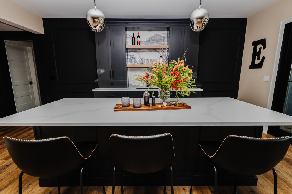 Inspiration for a large country seated home bar in Other with an undermount sink, shaker cabinets, quartz benchtops, white splashback, porcelain splashback, laminate floors and black benchtop.