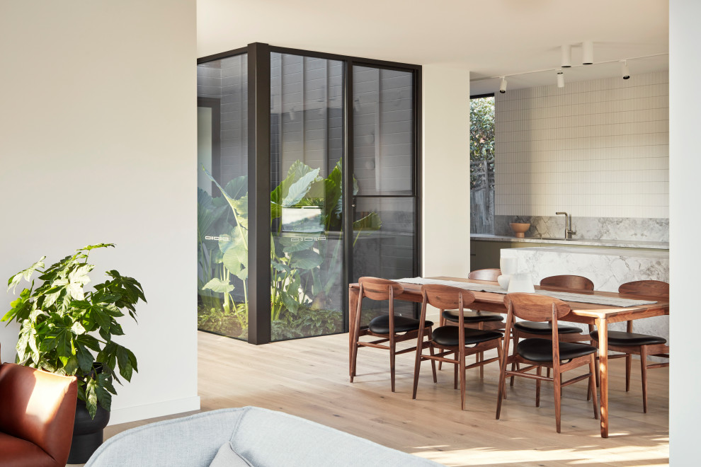 Design ideas for a large contemporary galley eat-in kitchen in Melbourne with a drop-in sink, flat-panel cabinets, green cabinets, marble benchtops, white splashback, ceramic splashback, stainless steel appliances, light hardwood floors, with island, beige floor and white benchtop.