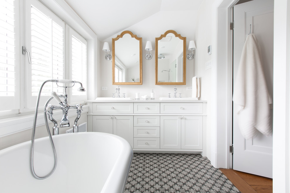 This is an example of a mid-sized traditional master bathroom in Montreal with a drop-in sink, shaker cabinets, white cabinets, granite benchtops, a freestanding tub, white tile, ceramic tile, white walls and ceramic floors.