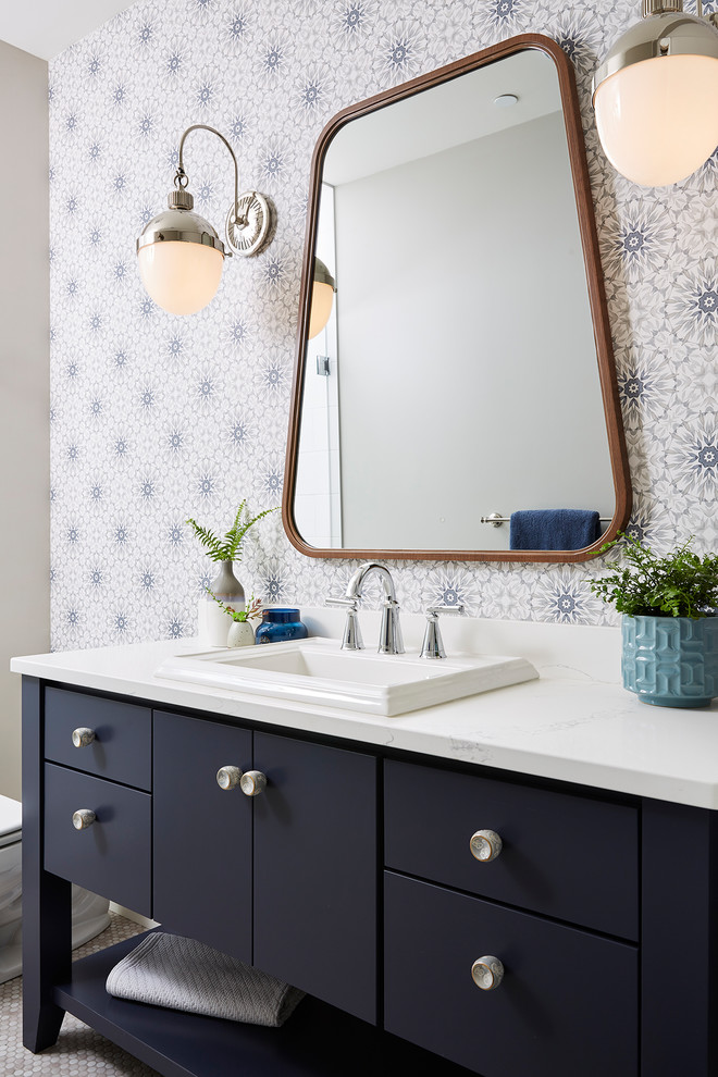 Transitional bathroom in Minneapolis with blue cabinets, engineered quartz benchtops, grey floor, white benchtops, flat-panel cabinets, multi-coloured walls and a drop-in sink.