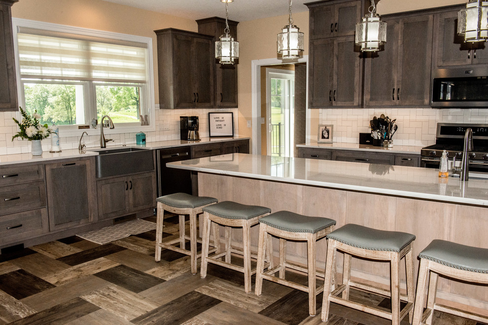 Inspiration for a large transitional l-shaped vinyl floor and multicolored floor open concept kitchen remodel with a farmhouse sink, shaker cabinets, gray cabinets, quartz countertops, white backsplash, subway tile backsplash, stainless steel appliances, an island and white countertops
