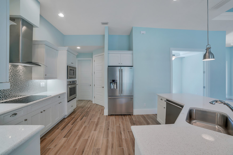 Inspiration for a mid-sized transitional u-shaped open concept kitchen remodel with a drop-in sink, recessed-panel cabinets, white cabinets, quartzite countertops, multicolored backsplash, mosaic tile backsplash, stainless steel appliances and an island