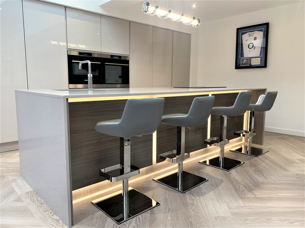 Medium sized contemporary single-wall kitchen/diner with a single-bowl sink, flat-panel cabinets, quartz worktops, black appliances, vinyl flooring, an island and beige worktops.
