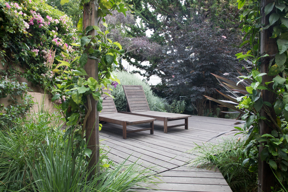 Imagen de jardín actual de tamaño medio en patio trasero con exposición parcial al sol, adoquines de ladrillo y con madera