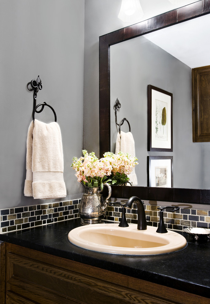 This is an example of a traditional powder room in Austin with a drop-in sink, multi-coloured tile and black benchtops.