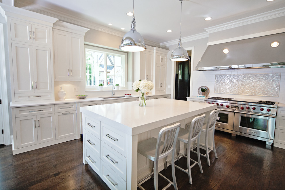 Design ideas for a large contemporary u-shaped eat-in kitchen in Chicago with an undermount sink, shaker cabinets, white cabinets, white splashback, subway tile splashback, stainless steel appliances, solid surface benchtops, dark hardwood floors, with island and white benchtop.