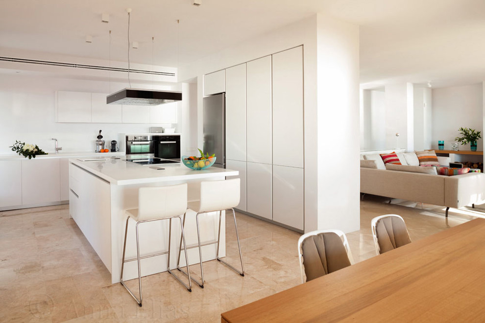 This is an example of a mid-sized contemporary single-wall open plan kitchen in Seville with flat-panel cabinets, white cabinets, white splashback, stainless steel appliances and with island.