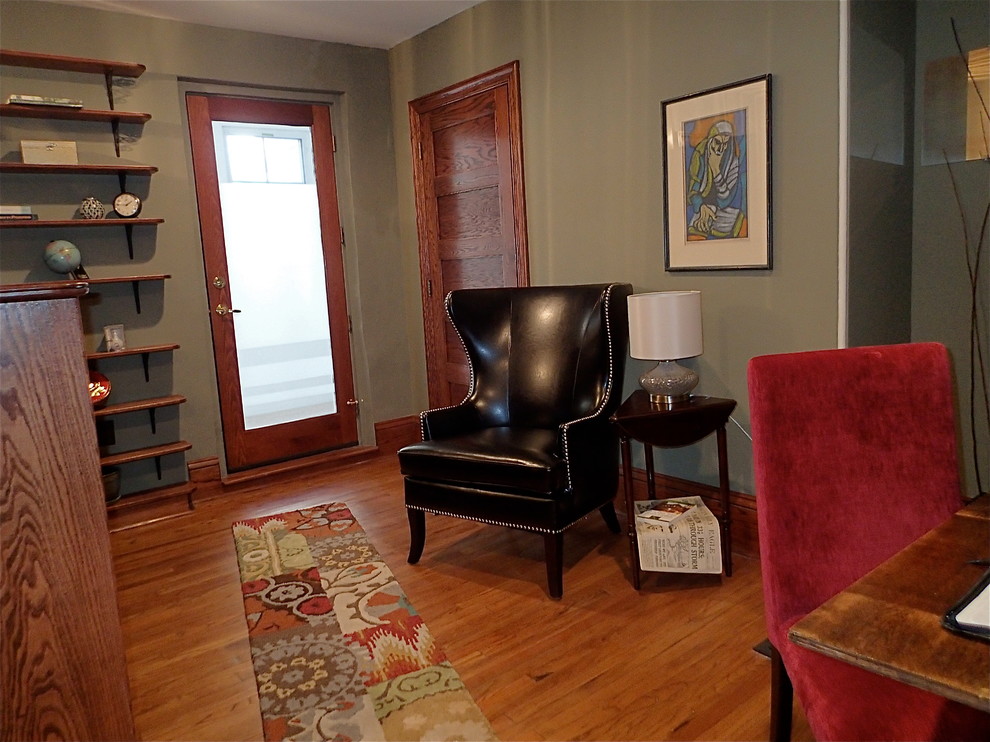 This is an example of a traditional open concept family room in Philadelphia with a library, green walls and medium hardwood floors.