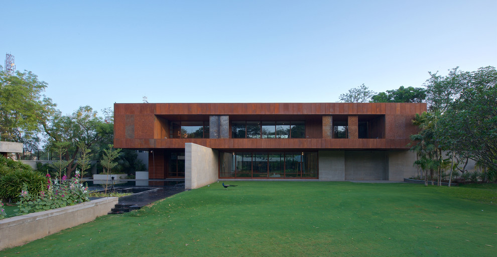 This is an example of a large contemporary two-storey exterior in Ahmedabad with mixed siding and a flat roof.