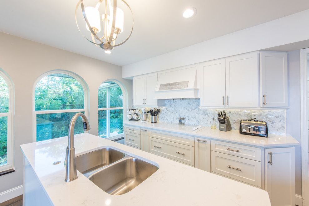 Eat-in kitchen - large transitional u-shaped porcelain tile and brown floor eat-in kitchen idea with an undermount sink, shaker cabinets, white cabinets, quartz countertops, white backsplash, marble backsplash, stainless steel appliances and two islands