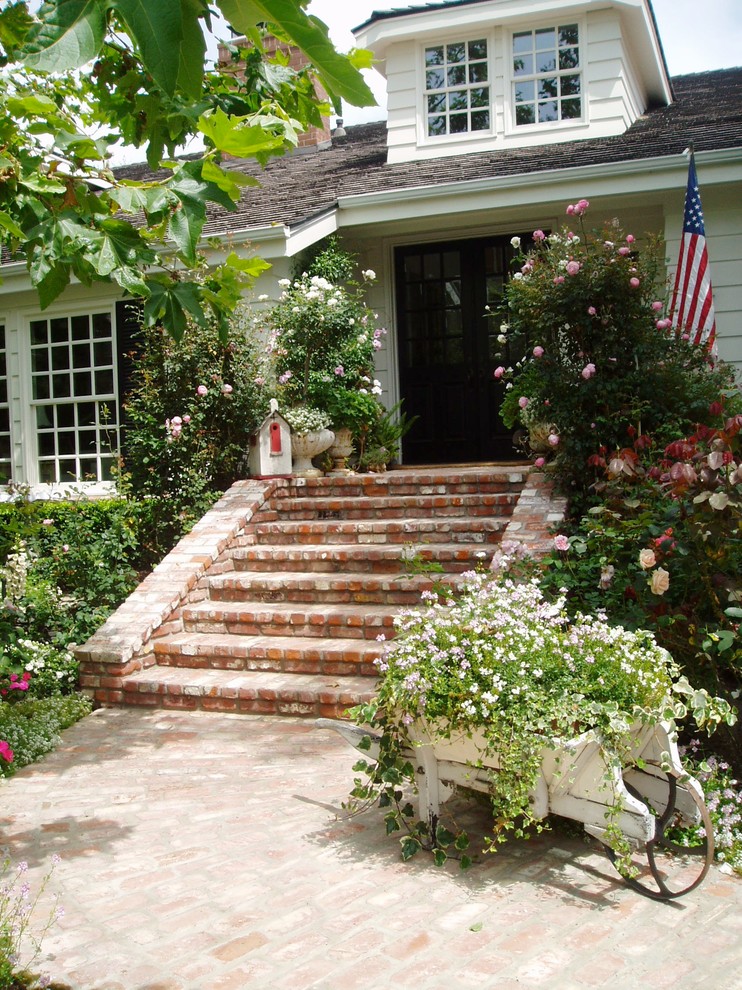 This is an example of a traditional front yard garden in San Diego with a container garden and brick pavers.