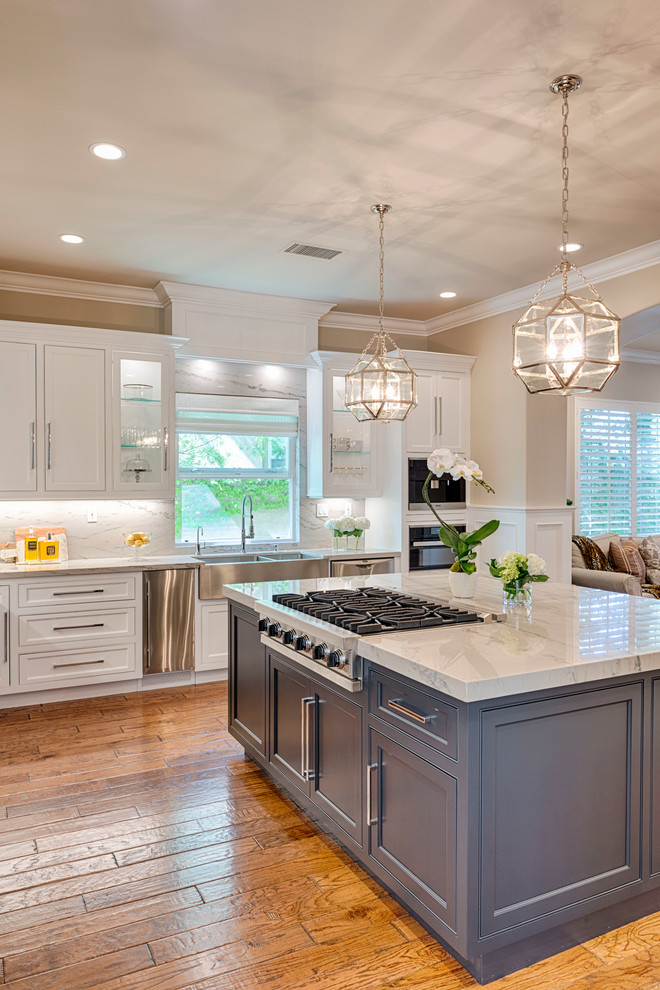 Large transitional l-shaped medium tone wood floor eat-in kitchen photo in Orange County with a drop-in sink, quartzite countertops, white backsplash, stone slab backsplash, stainless steel appliances, an island, beaded inset cabinets and white cabinets