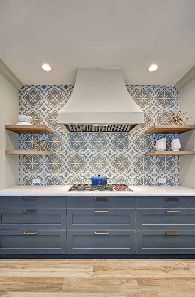 Large transitional l-shaped eat-in kitchen in Sacramento with an undermount sink, recessed-panel cabinets, blue cabinets, quartz benchtops, grey splashback, ceramic splashback, stainless steel appliances, porcelain floors, with island, beige floor and white benchtop.