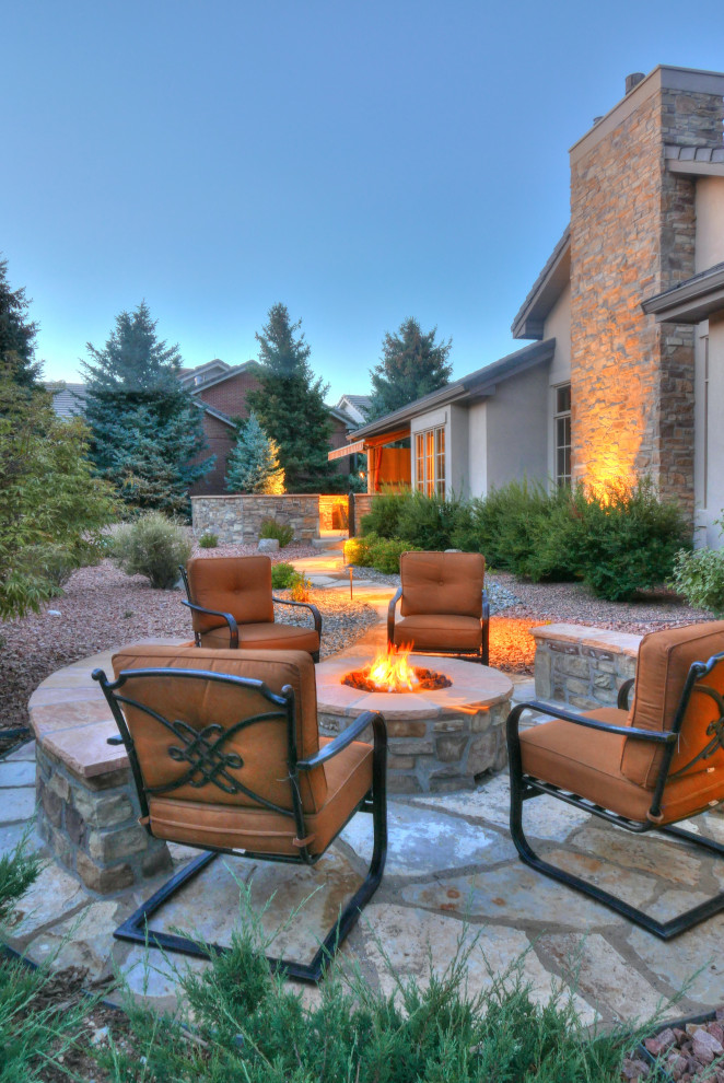 Photo of a mid-sized traditional backyard full sun xeriscape for winter in Denver with a fire feature and natural stone pavers.