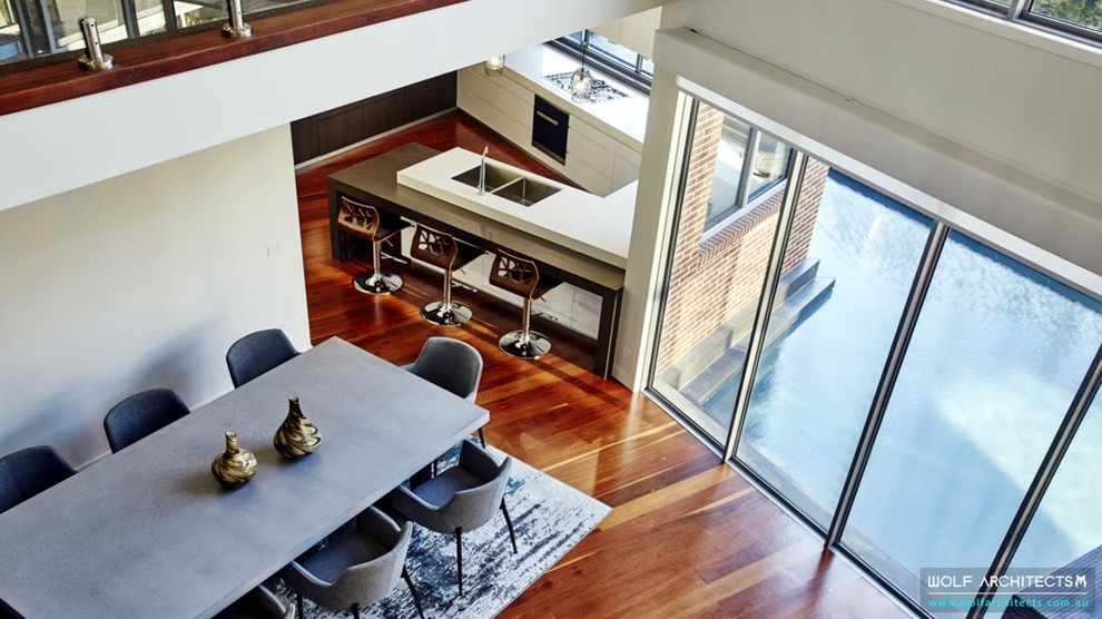Inspiration for a mid-sized contemporary kitchen/dining combo in Melbourne with beige walls, medium hardwood floors and brown floor.