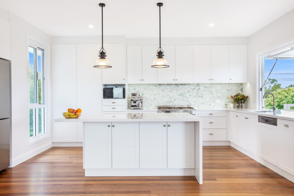 Inspiration for a mid-sized beach style u-shaped open plan kitchen in Central Coast with multi-coloured splashback, glass tile splashback, stainless steel appliances and with island.