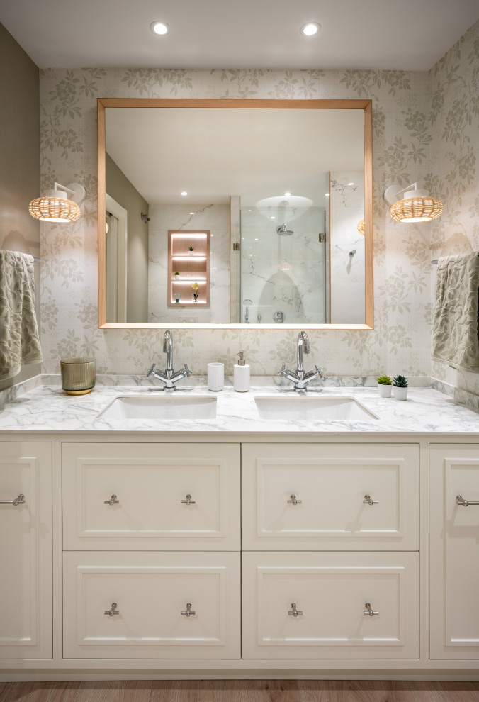 Photo of a mid-sized transitional master bathroom in Other with raised-panel cabinets, white cabinets, a curbless shower, white tile, green walls, laminate floors, an undermount sink, granite benchtops, brown floor, white benchtops, a double vanity, a built-in vanity and wallpaper.