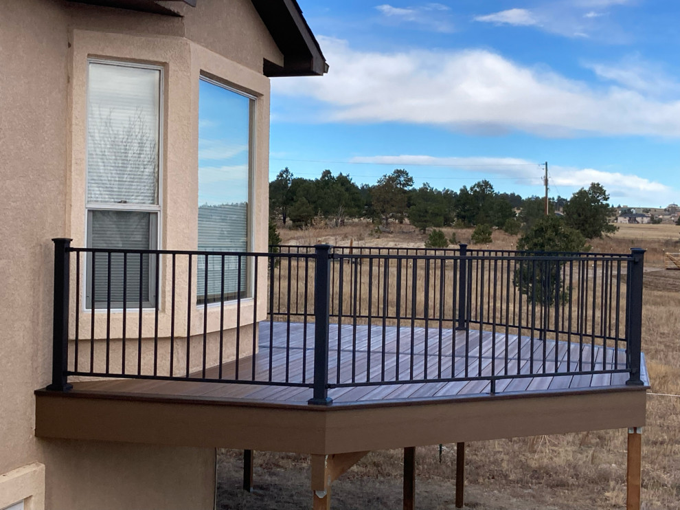 Example of a mid-sized mountain style ground level metal railing deck design in Denver