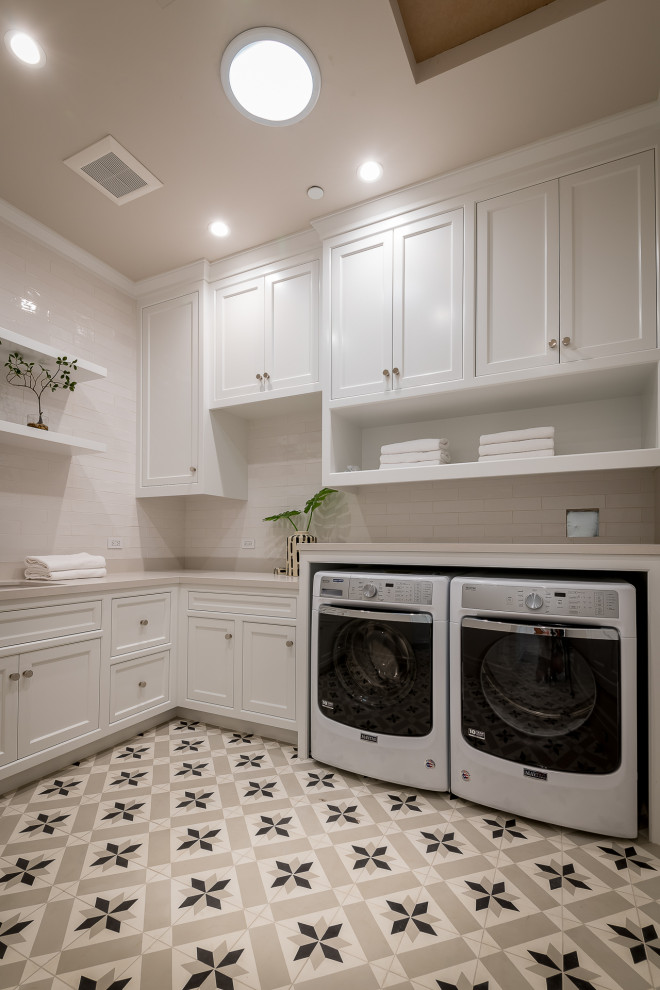 This is an example of a mid-sized country dedicated laundry room in Los Angeles with a double-bowl sink, raised-panel cabinets, marble benchtops, ceramic splashback, ceramic floors, a concealed washer and dryer, multi-coloured floor and white benchtop.
