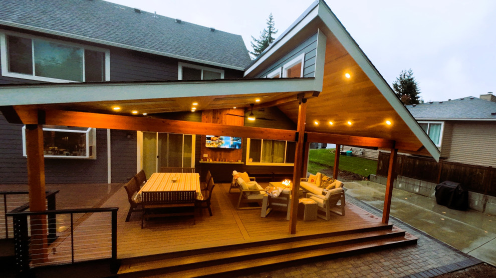 Inspiration for a large craftsman backyard ground level cable railing deck remodel in Seattle with a fire pit and a roof extension