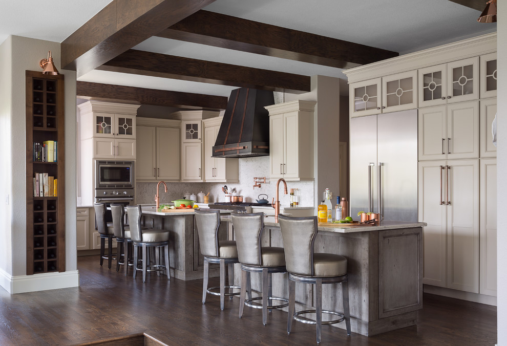 Design ideas for a large transitional l-shaped open plan kitchen in Denver with recessed-panel cabinets, beige cabinets, white splashback, stainless steel appliances, dark hardwood floors, with island, brown floor, white benchtop, a farmhouse sink, marble benchtops and stone slab splashback.