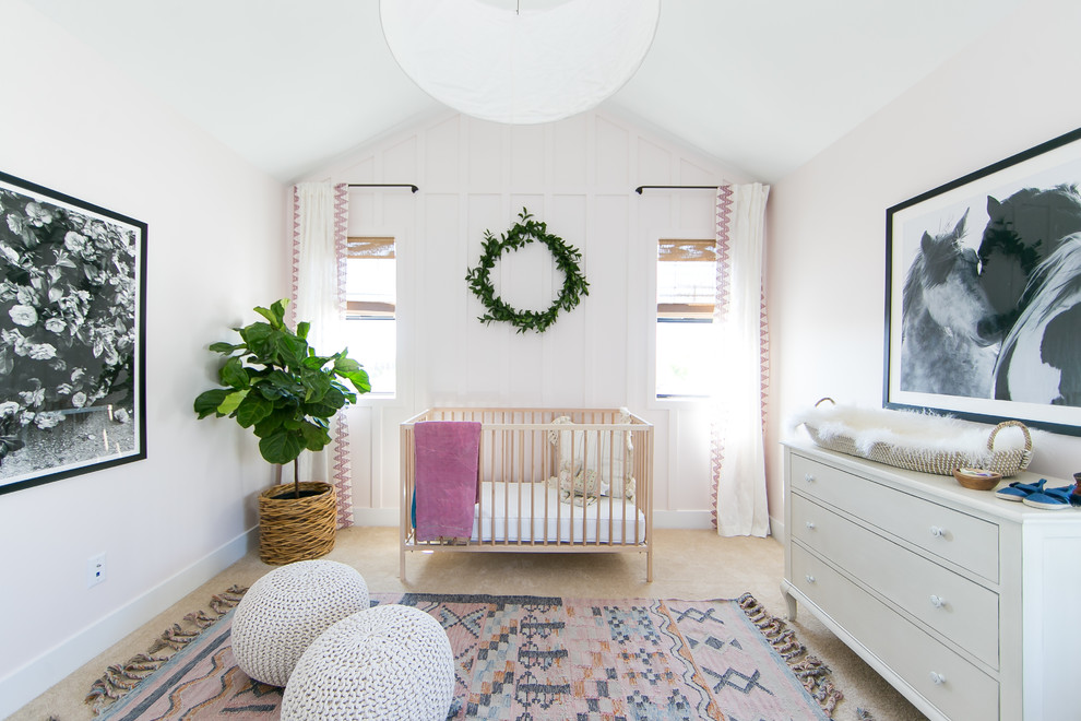 This is an example of a beach style nursery for girls in Orange County with pink walls, carpet and beige floor.
