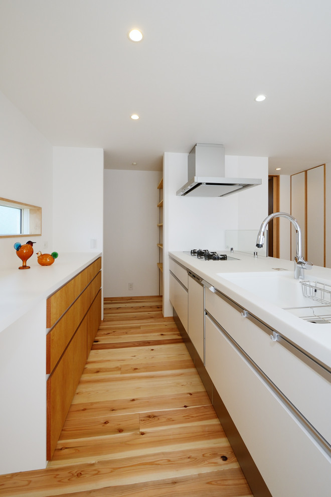 Bild på ett mellanstort nordiskt vit linjärt vitt kök med öppen planlösning, med en integrerad diskho, släta luckor, vita skåp, bänkskiva i koppar, vitt stänkskydd, vita vitvaror, mellanmörkt trägolv, en halv köksö och beiget golv