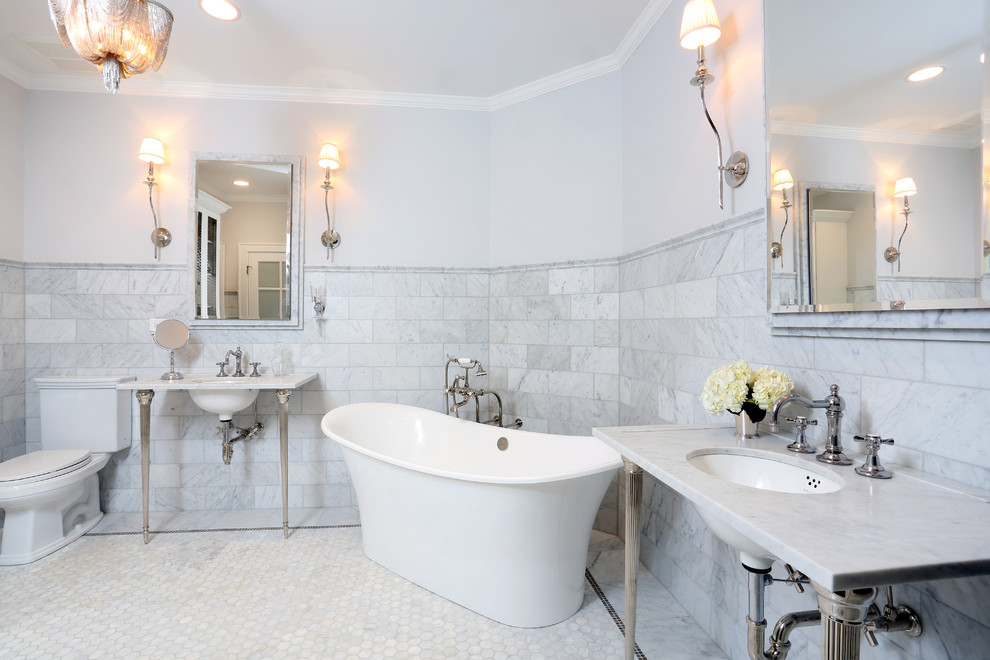 This is an example of a large traditional master bathroom in Chicago with a pedestal sink, a freestanding tub, a two-piece toilet, white tile, stone tile and grey walls.