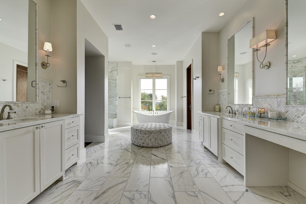 Photo of a transitional bathroom in Austin with shaker cabinets, white cabinets, a freestanding tub, an alcove shower, gray tile, white tile, marble floors and an undermount sink.
