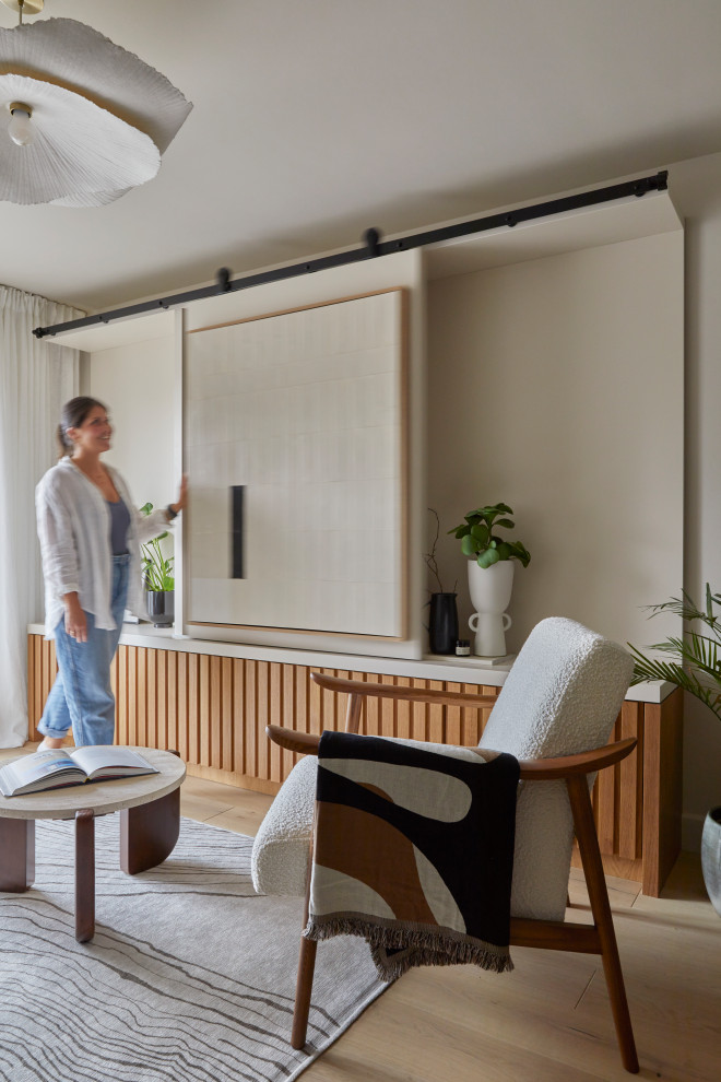 Inredning av ett modernt litet separat vardagsrum, med beige väggar, ljust trägolv och en dold TV