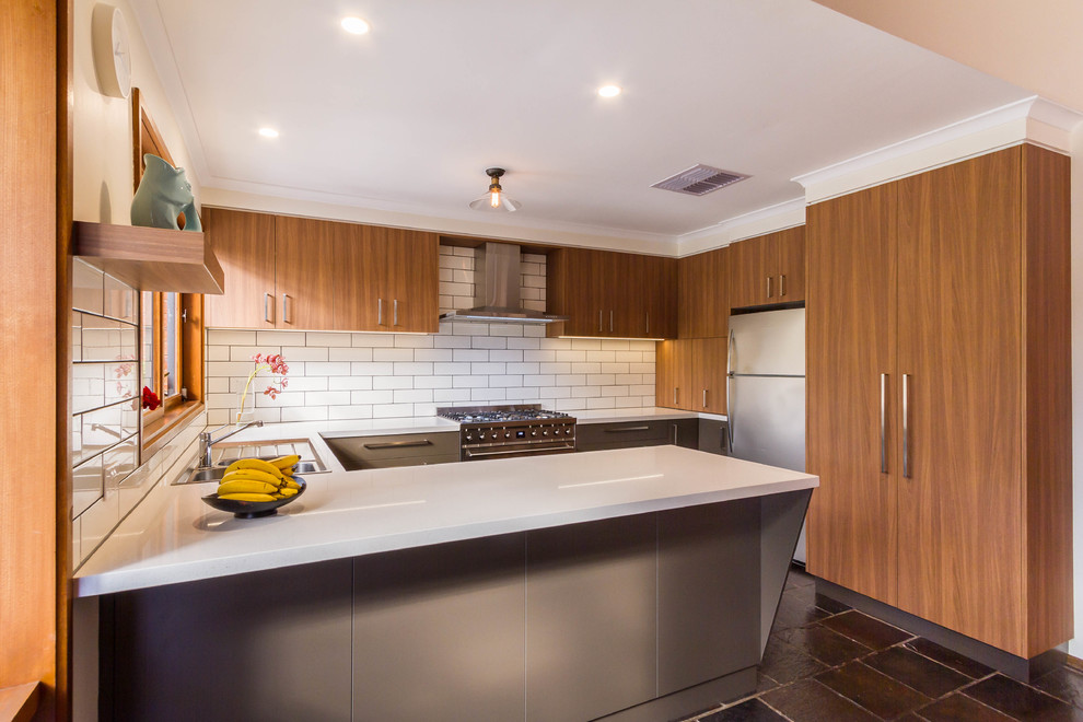 Mid-sized midcentury u-shaped eat-in kitchen in Melbourne with a drop-in sink, flat-panel cabinets, grey cabinets, quartz benchtops, white splashback, ceramic splashback, stainless steel appliances, slate floors, a peninsula, grey floor and white benchtop.