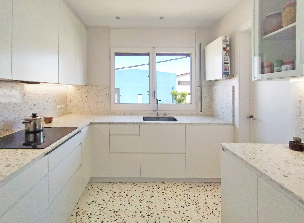Photo of a small modern u-shaped separate kitchen in Other with an undermount sink, flat-panel cabinets, white cabinets, terrazzo benchtops, grey splashback, granite splashback, panelled appliances, terrazzo floors, no island, multi-coloured floor and grey benchtop.
