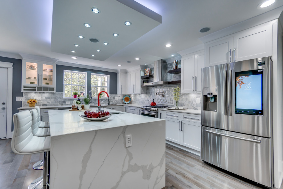 Inspiration for a large modern l-shaped kitchen/diner in DC Metro with a built-in sink, shaker cabinets, white cabinets, marble worktops, grey splashback, mosaic tiled splashback, stainless steel appliances, plywood flooring, an island, grey floors and white worktops.