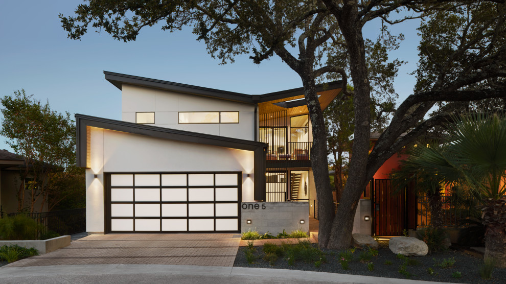 Diseño de fachada de casa blanca y negra minimalista de tamaño medio con revestimiento de estuco, techo de mariposa y tejado de metal