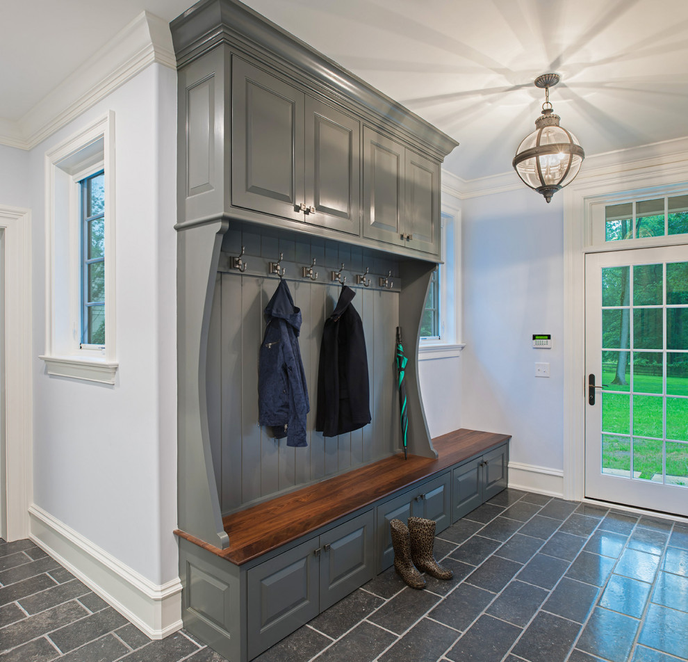 Inspiration for a mid-sized mudroom with white walls, concrete floors, a single front door, a white front door and grey floor.