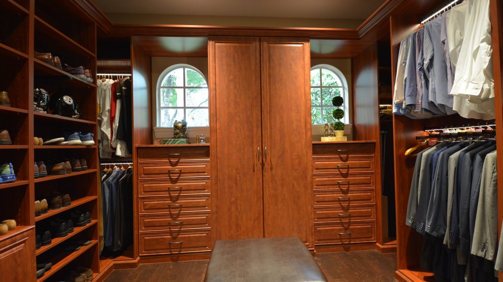 Inspiration for a mid-sized traditional men's walk-in wardrobe in Orange County with raised-panel cabinets, medium wood cabinets and dark hardwood floors.