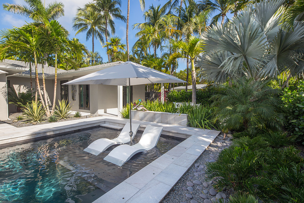 This is an example of a mid-sized tropical backyard pool in Miami.