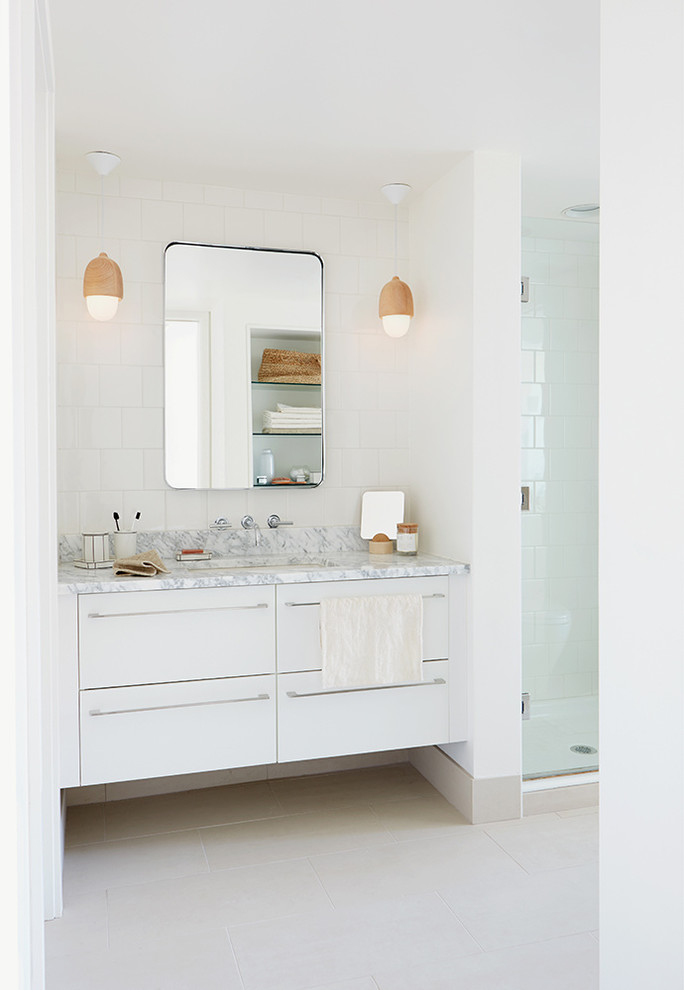 This is an example of a small scandinavian 3/4 bathroom in Seattle with flat-panel cabinets, white cabinets, an alcove shower, a two-piece toilet, white tile, ceramic tile, white walls, porcelain floors, an undermount sink, marble benchtops, beige floor and a hinged shower door.