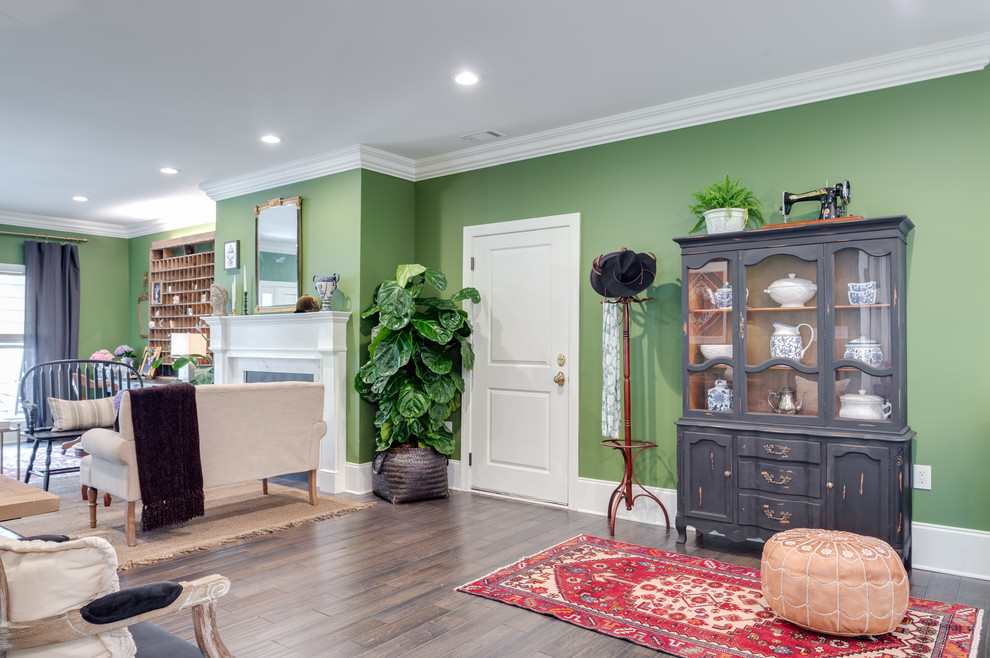This is an example of a large contemporary formal open concept living room in Atlanta with green walls, dark hardwood floors, a standard fireplace, a plaster fireplace surround, no tv and brown floor.
