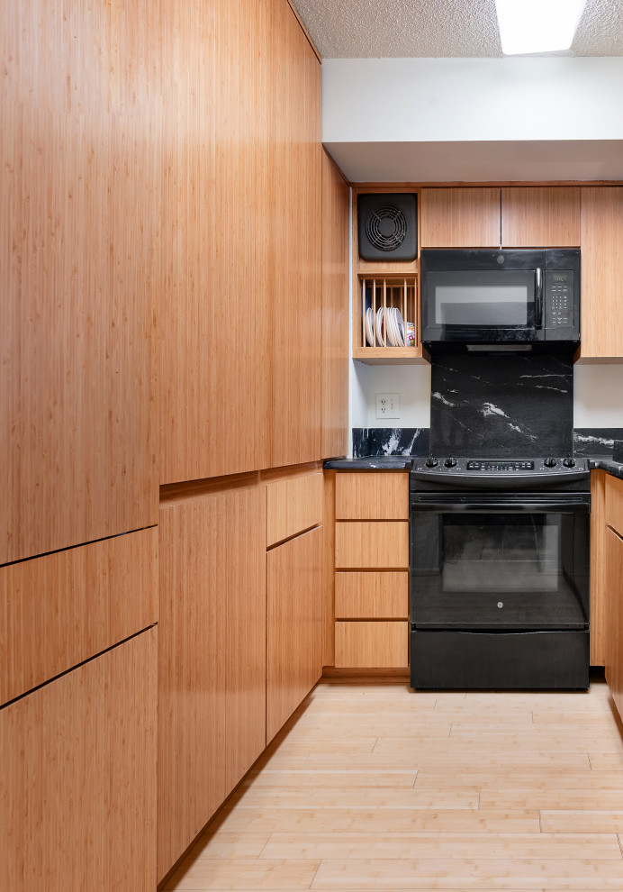 Small contemporary u-shaped separate kitchen with an integrated sink, flat-panel cabinets, medium wood cabinets, quartz benchtops, black splashback, black appliances, light hardwood floors and no island.