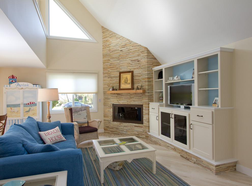 Mid-sized beach style open concept living room in Other with light hardwood floors, a corner fireplace, a stone fireplace surround, a built-in media wall, beige walls and yellow floor.