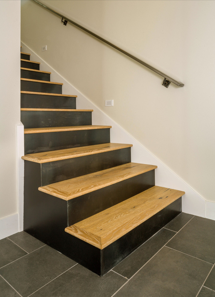 This is an example of a mid-sized modern wood straight staircase in Seattle with metal risers and metal railing.