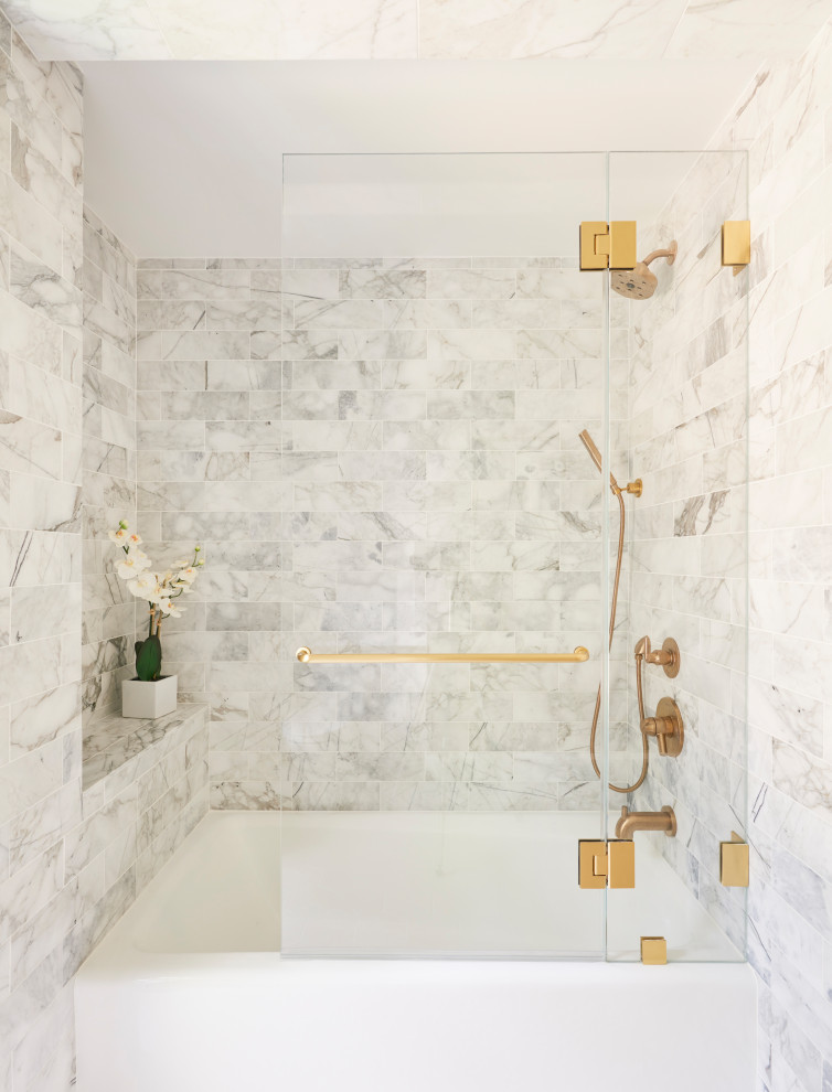 This is an example of a large beach style 3/4 bathroom in New York with recessed-panel cabinets, medium wood cabinets, an alcove tub, a shower/bathtub combo, a one-piece toilet, gray tile, marble, white walls, ceramic floors, a wall-mount sink, laminate benchtops, white floor, a hinged shower door and white benchtops.