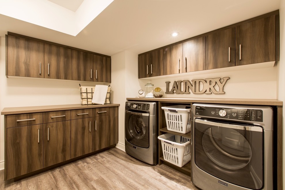 Example of a mid-sized transitional l-shaped medium tone wood floor and brown floor dedicated laundry room design with flat-panel cabinets, beige walls, a side-by-side washer/dryer and dark wood cabinets