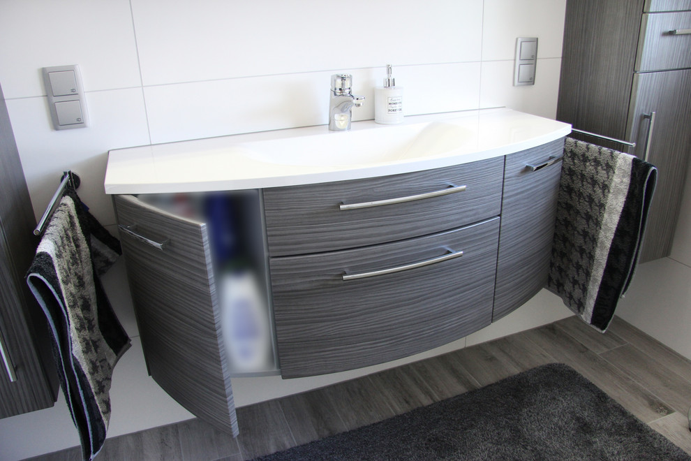 Badezimmer With Eckbadewanne, Eckdusche, Wandtoilette, weißen Fliesen, Keramikfliesen, weißer Wandfarbe, Zementfliesen für Boden, Wandwaschbecken, braunem Boden and Falttür-Duschabtrennung in Munich