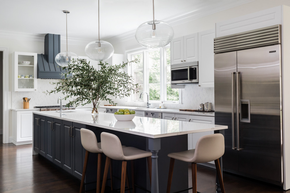 Inspiration for a transitional l-shaped kitchen in Boston with an undermount sink, raised-panel cabinets, white cabinets, white splashback, mosaic tile splashback, stainless steel appliances, dark hardwood floors, with island, brown floor and white benchtop.