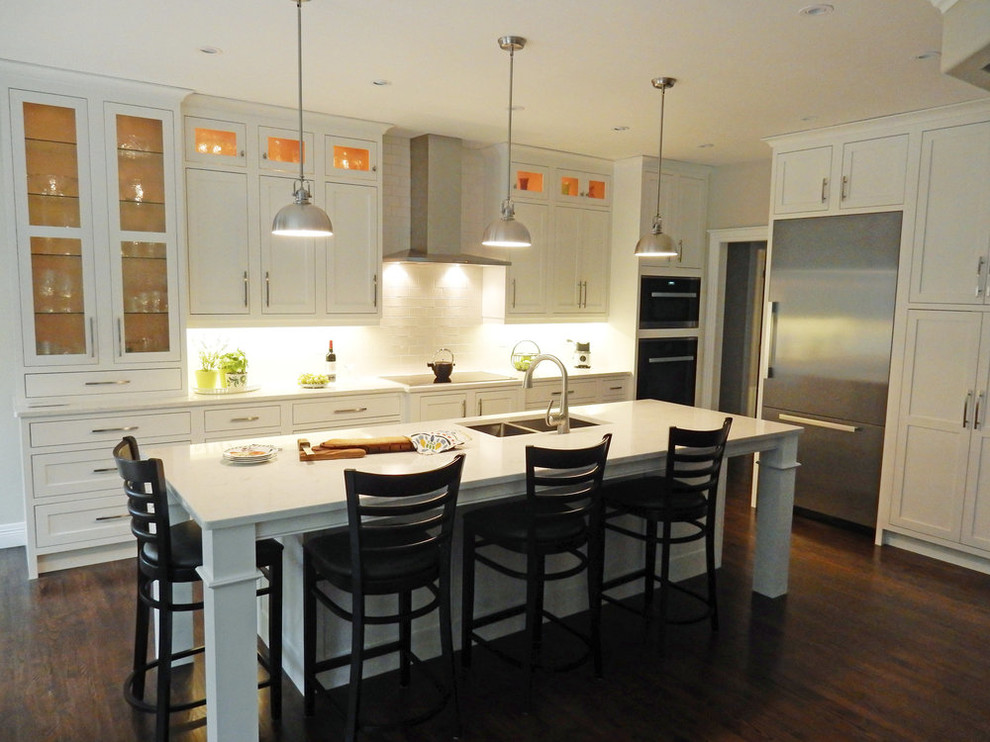 Inspiration for a mid-sized transitional l-shaped dark wood floor and brown floor open concept kitchen remodel with a double-bowl sink, beaded inset cabinets, white cabinets, quartz countertops, white backsplash, glass tile backsplash, stainless steel appliances, an island and white countertops